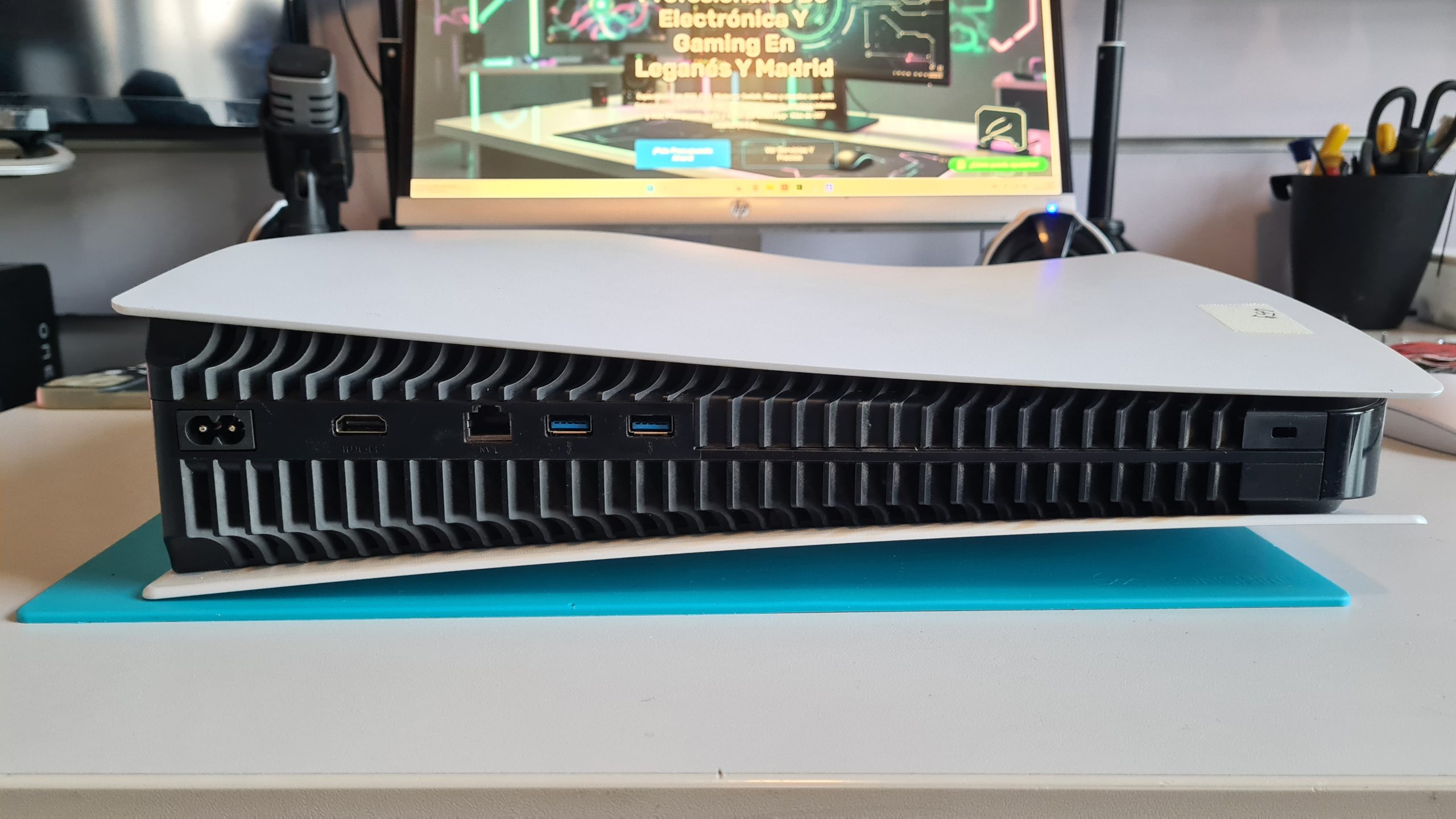 PS5 tumbada en mesa de taller GameSystems Leganés mostrando parte trasera con conexiones HDMI